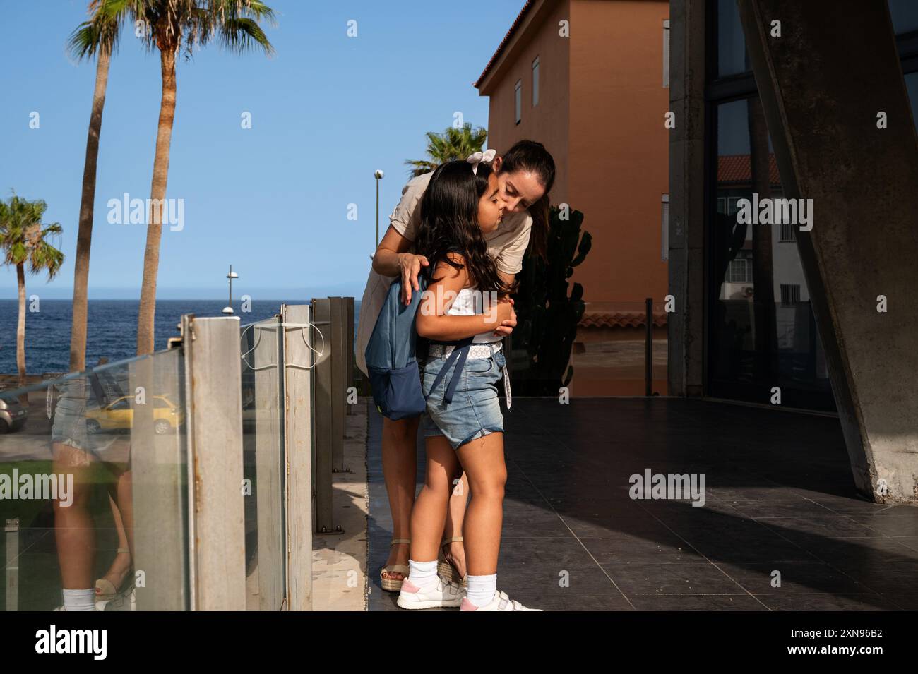Die Mutter küsst die Tochter vor dem Schuleintritt am ersten Schultag Stockfoto