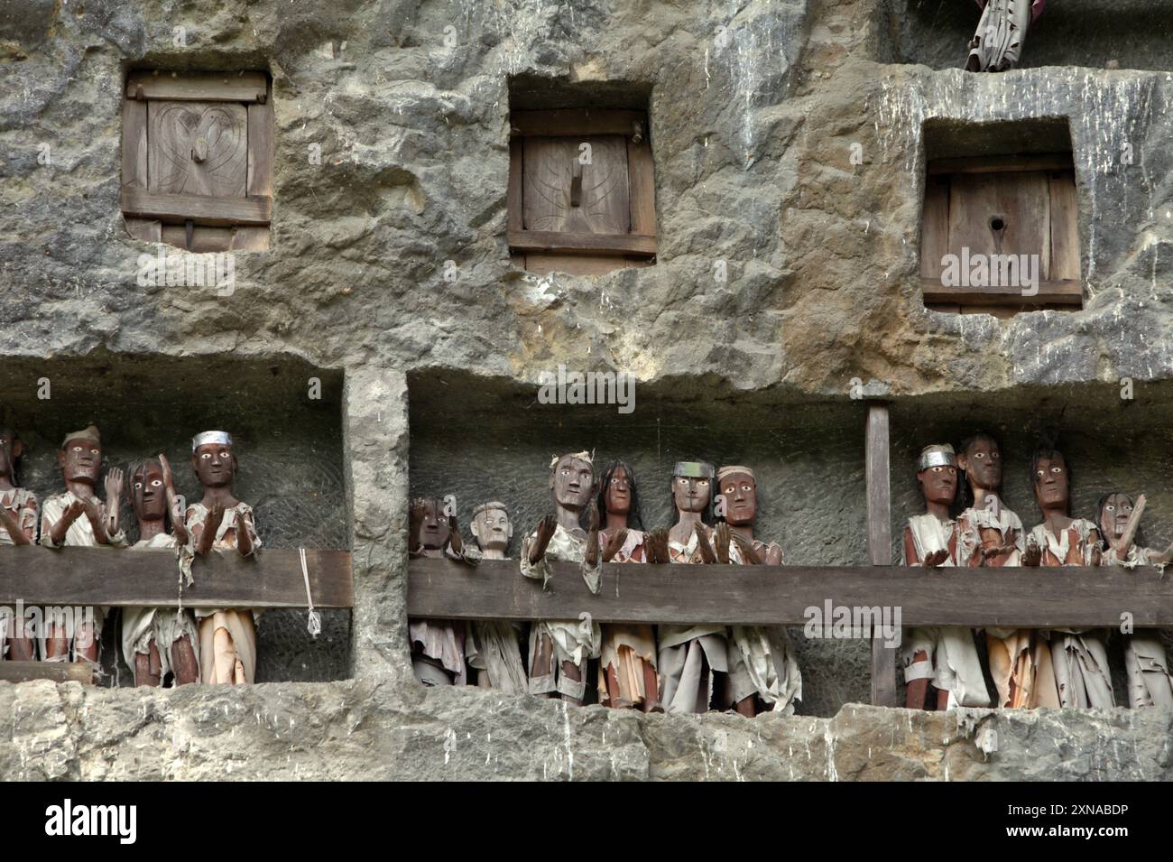 Steingrabeöffnungen und Holzraster auf einer Klippe an einer traditionellen Grabstätte in Lemo, Nord-Toraja, Süd-Sulawesi, Indonesien. Stockfoto