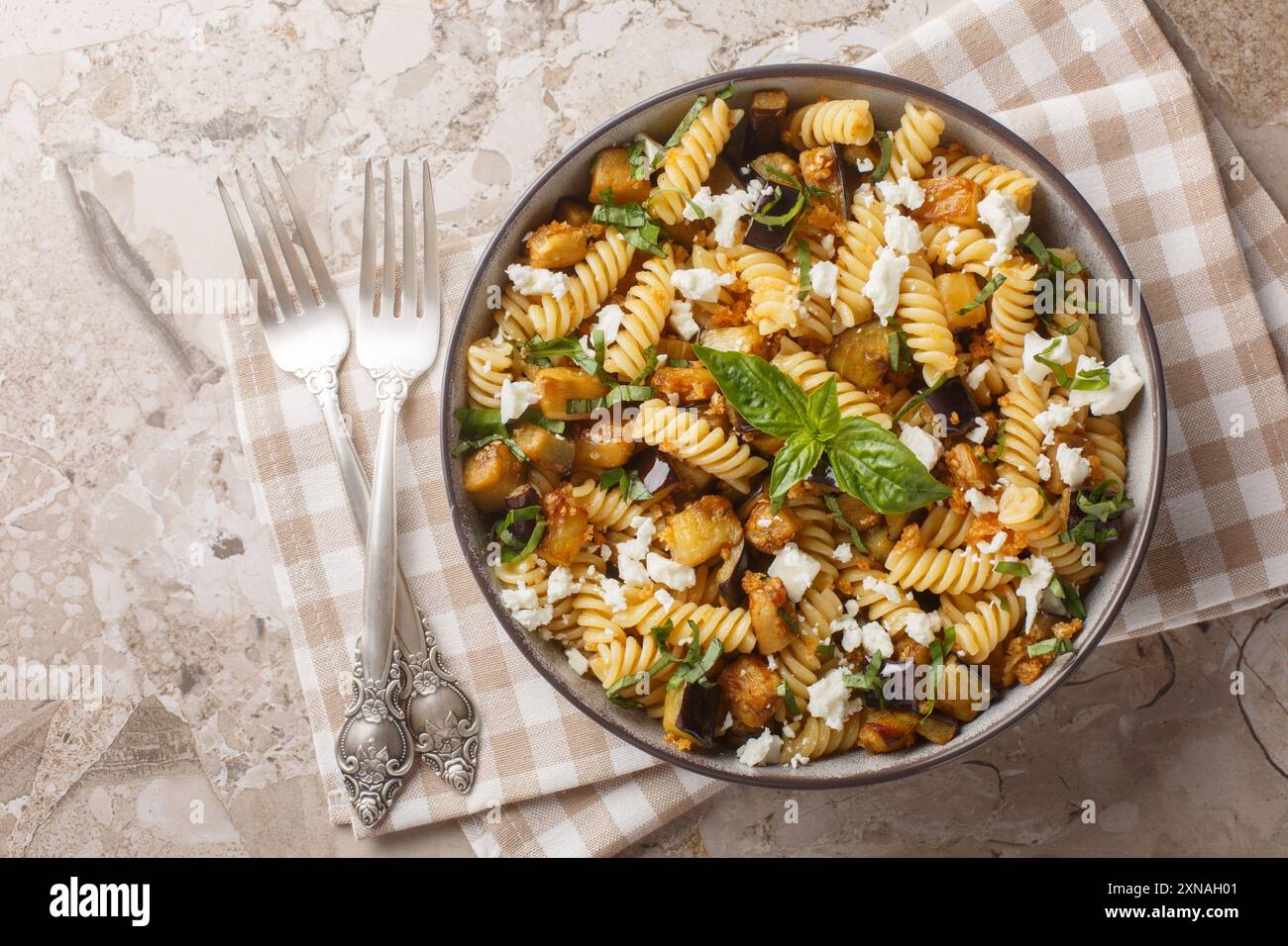 Scharfe Fusilli-Pasta mit gebratener Aubergine, Knoblauch, Fetakäse und Brotkrumen in einer Schüssel auf dem Tisch. Horizontale Draufsicht von oben Stockfoto