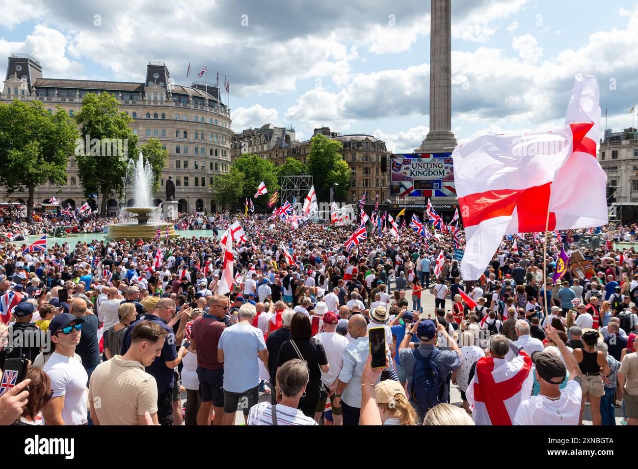 Massen von Tommy-Robinson-Anhängern am Trafalgar Square für die Demonstration von Uniting the Kingdom mit Großbildleinwand und Bühne. England-Flaggen Stockfoto