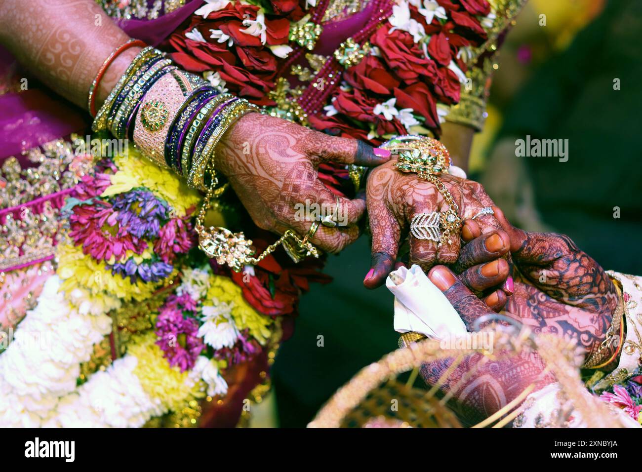 Zärtliche Hände einer indischen Braut, bedeckt mit Henna-Tattoo, halten die Hand des Bräutigams, Ringzeremonie. Stockfoto