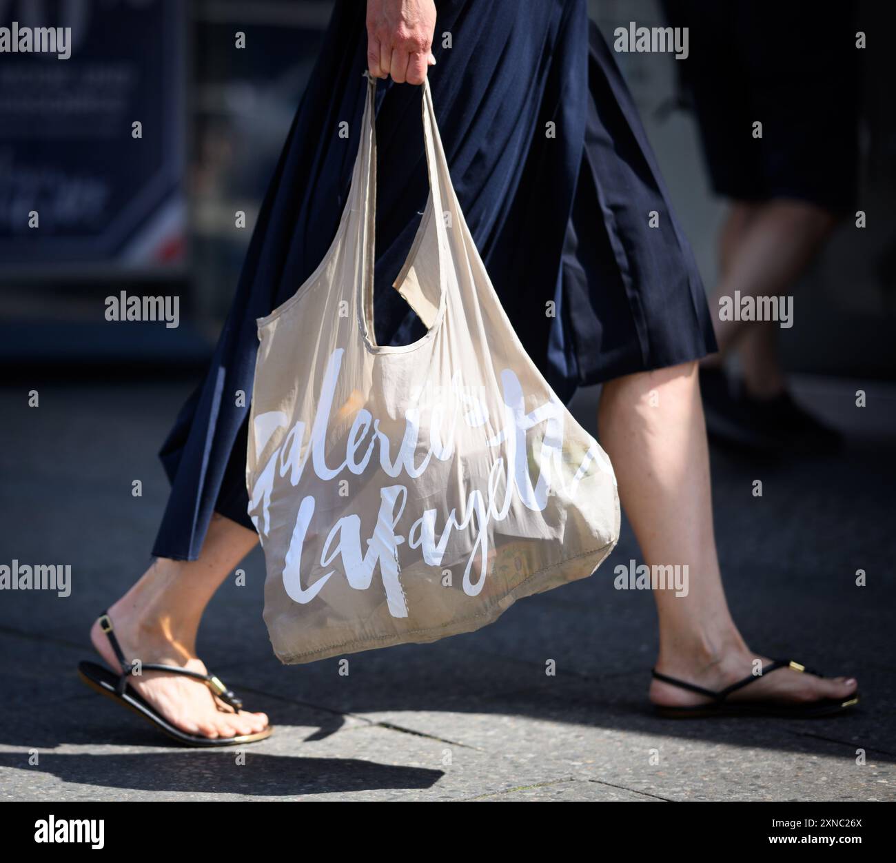 Berlin, Deutschland. 31. Juli 2024. Eine Frau kommt aus dem Luxuskaufhaus Galeries Lafayette in der Friedrichstraße in Berlin-Mitte mit einer Einkaufstasche. Die französische Kaufhauskette Galeries Lafayette schließt heute ihre Berliner Filiale im Quartier 207. Der Berliner Senat erwägt, die Zentral- und Landesbibliothek Berlin (ZLB) in den Gebäudekomplex einzuziehen. Quelle: Bernd von Jutrczenka/dpa/Alamy Live News Stockfoto