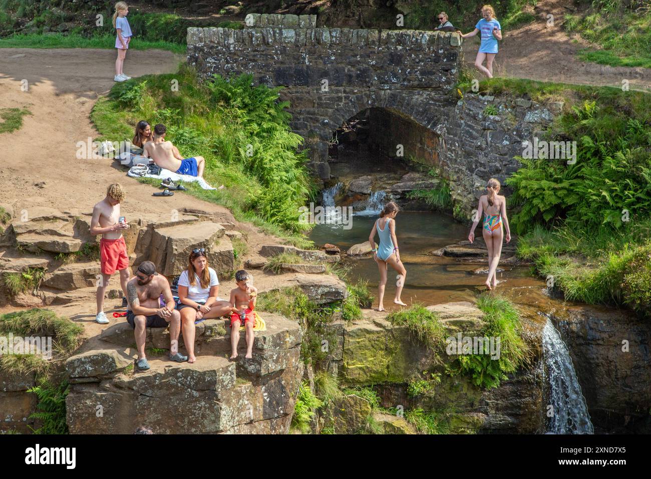 Besucher genießen die Sommersonne des Jahres 2024 am Peak District Beauty Spot des Three Shires Head, wo sich Cheshire Derbyshire und Staffordshire treffen Stockfoto