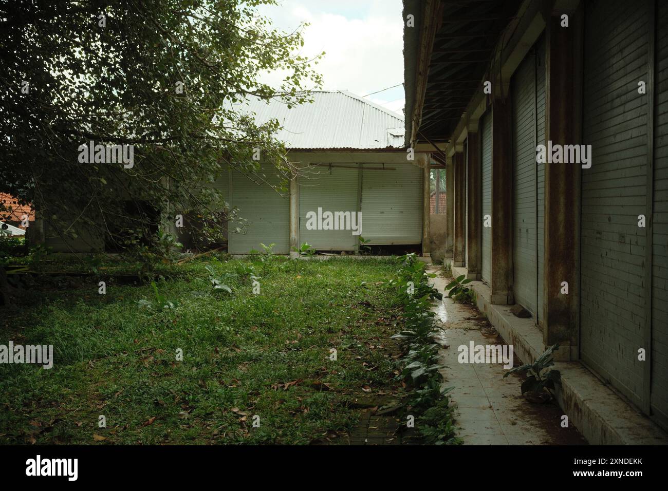 Mehrere Kioske oder Ladengeschäfte für kleine Unternehmen sind aufgrund globaler wirtschaftlicher Probleme zu verlassenen Gebäuden geworden, die von wilden Pflanzen überlaufen sind Stockfoto
