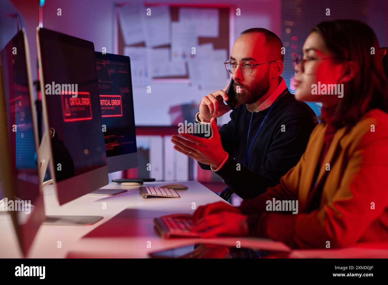 Porträt eines aufgeregten Cybersicherheitsteams, das im Notfallmodus arbeitet, mit kritischer Fehlermeldung auf dem Computerbildschirm Stockfoto