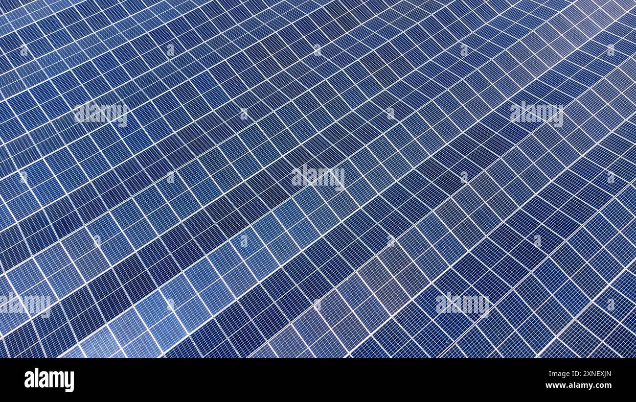 Nahaufnahme einer umfangreichen Reihe blauer Solarpaneele, die auf Kipprahmen montiert und schräg montiert sind. Solarenergie. Stockfoto