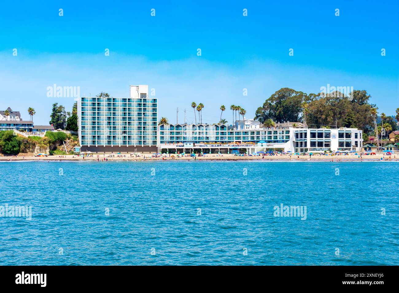 Malerische Aussicht auf Dream Inn vom Wasser aus. Hauptstrand voller Strandgänger, die die Sonne und das Surfen am Sandstrand genießen - Santa Cruz, Californ Stockfoto