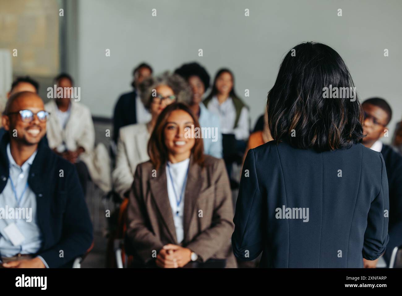 Geschäftsfrau präsentiert sich bei einem Meeting vor einer Gruppe lächelnder Kollegen und Kollegen. Professionelle Interaktion und Diskussion. Stockfoto Geschäftsfrau präsentiert sich bei einem Meeting vor einer Gruppe lächelnder Kollegen und Kollegen. Professionelle Interaktion und Diskussion. Stockfoto