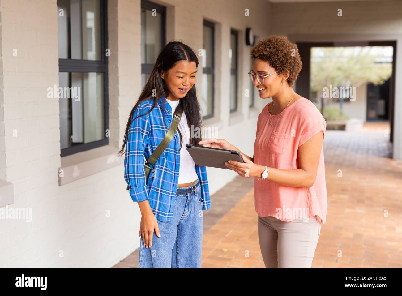 In der Highschool zeigte der Lehrer dem Schüler ein Tablet im Flur und diskutierte über die Arbeit Stockfoto
