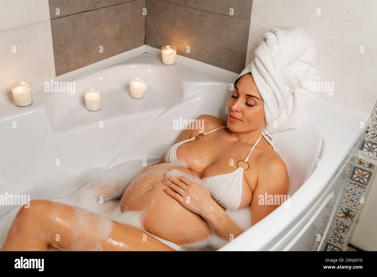 Schwangere Frau genießt ein Blasenbad Stockfoto