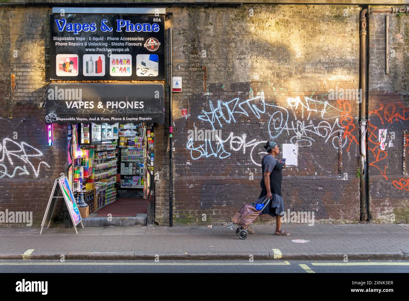 Eine Frau spaziert entlang der Rye Lane in Peckham Rye, South London. Stockfoto