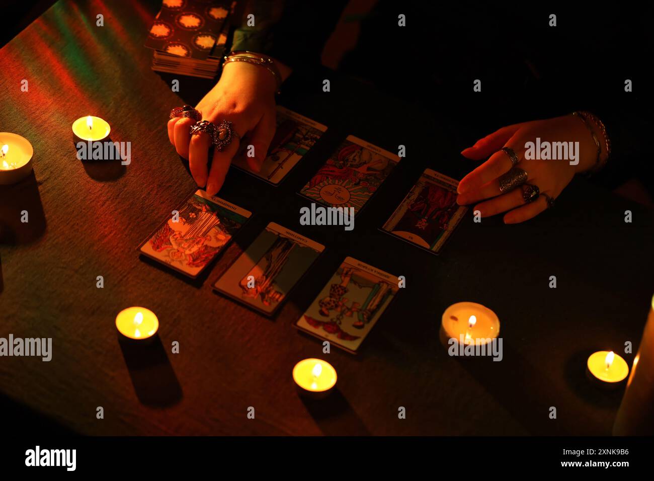 KIEW, UKRAINE - 10. JULI 2024 Tarotleser wählt Tarotkarten aus. Kerzenlicht im dunklen Raum. Tarot-Leser oder Wahrsager lesen und Prognosen aus nächster Nähe Stockfoto