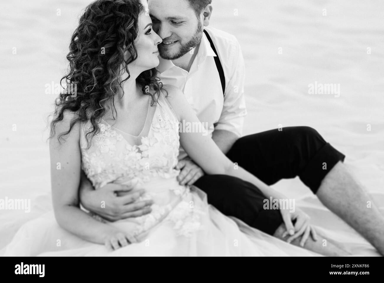 Ein junges Paar, ein Mann in schwarzen Hosen und ein Mädchen in einem rosa Kleid, laufen entlang des weißen Sands der Wüste Stockfoto