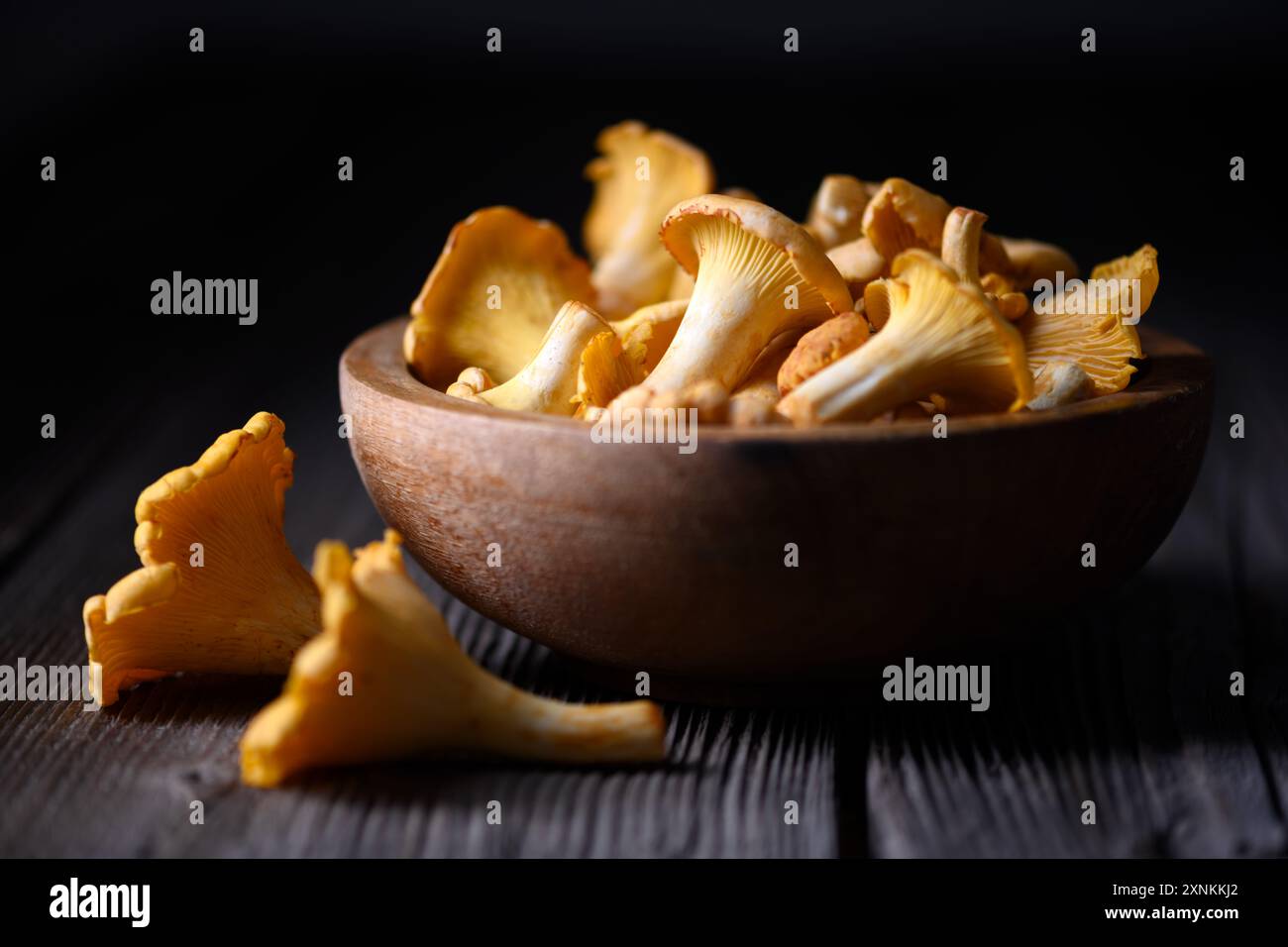 Pfifferlingen in einer Holzschale auf rustikalem Holztisch aus nächster Nähe. Lebensmittelfotografie Stockfoto