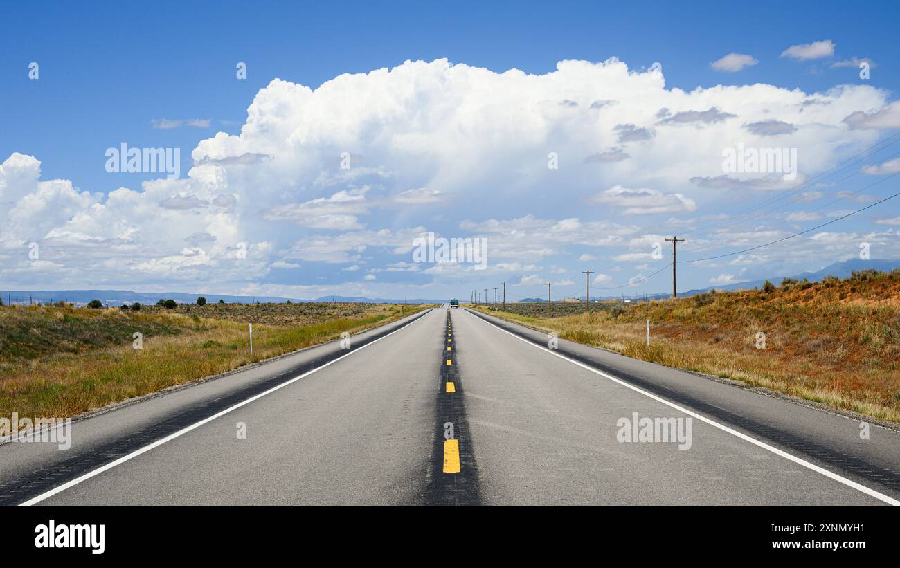 Zweispurige Straße, die offene Hochwüste in Richtung großer weißer Wolke führt Stockfoto