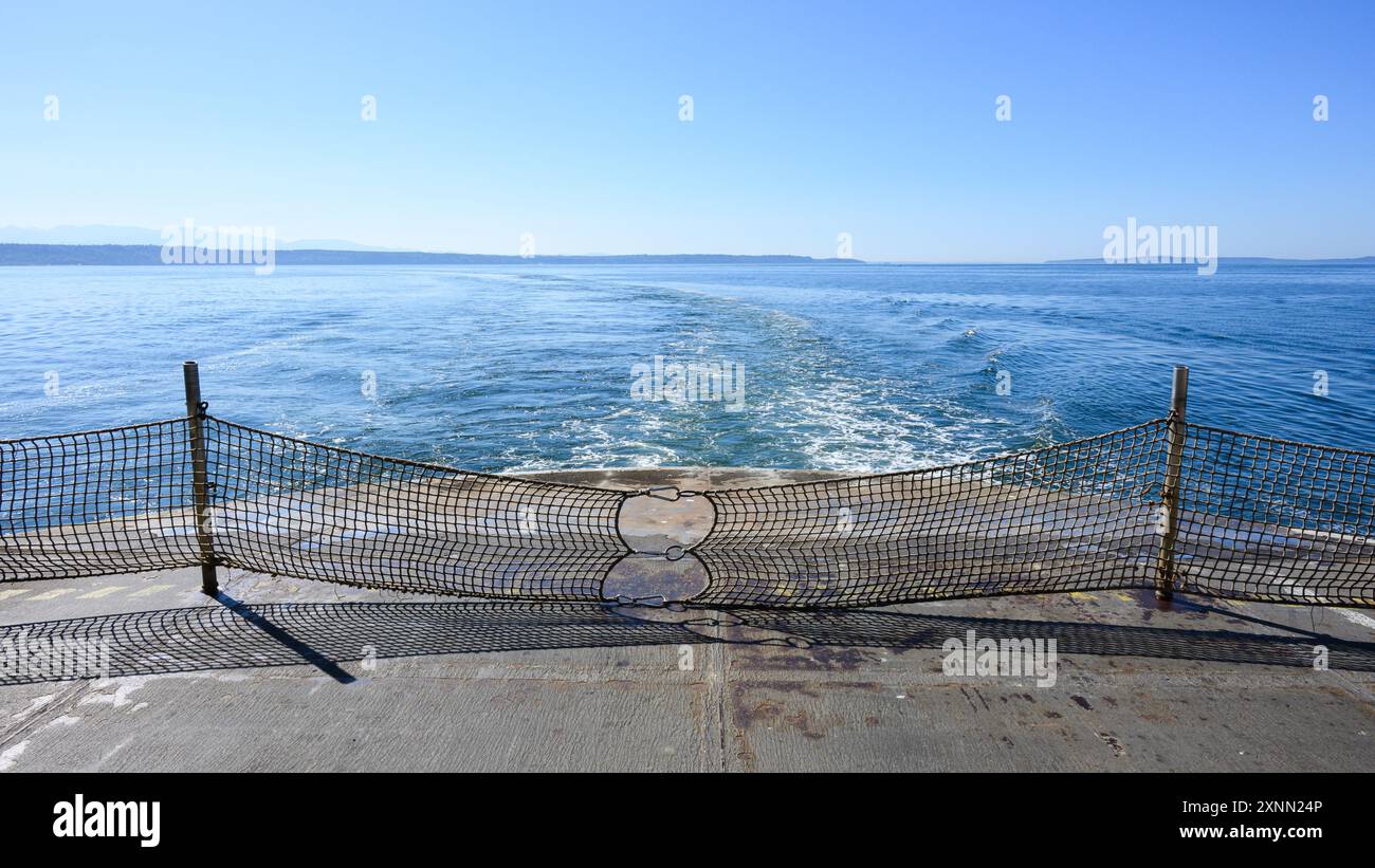 Panoramablick hinten auf das Deck der Autofähre, während das Boot unter klarem Himmel in blauem Wasser gewaschen wird Stockfoto