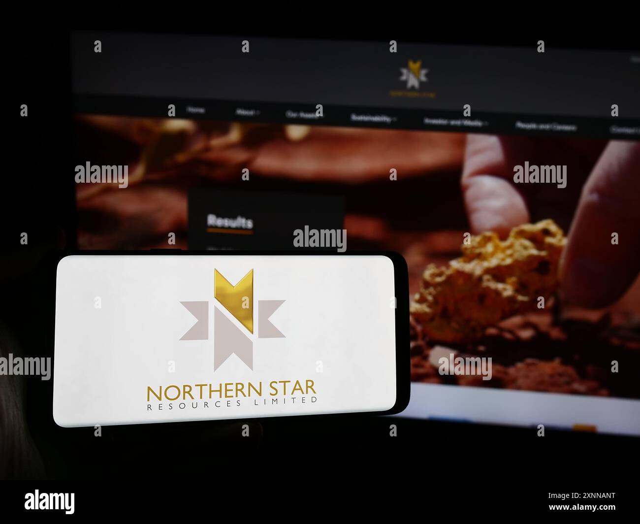 Person, die ein Mobiltelefon mit dem Logo des australischen Unternehmens Northern Star Resources Limited vor der Webseite des Unternehmens hält. Schwerpunkt auf dem Display des Telefons. Stockfoto