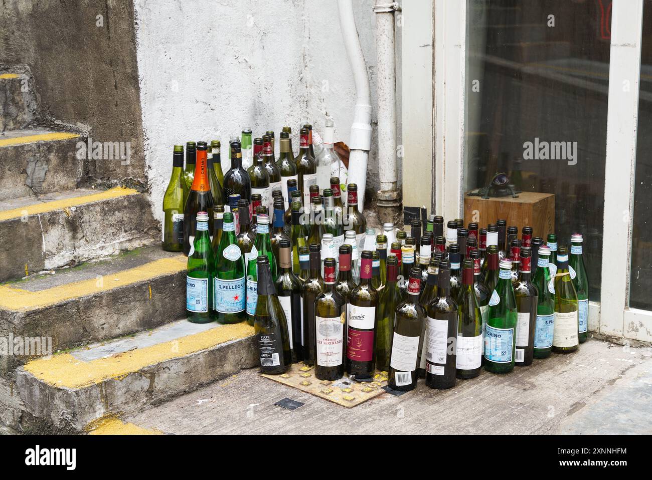 Eine Auswahl leerer Bären- und Weinflaschen vor einer Bar auf einigen Stufen. Hongkong - 27. Mai 2024 Stockfoto