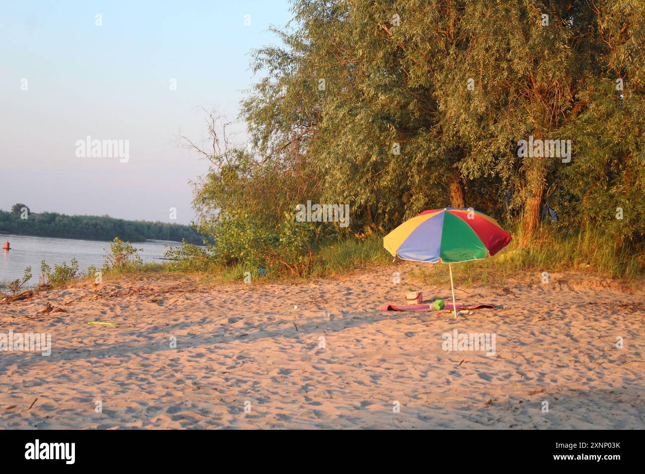 regenbogenschirm am Strand. Das Konzept eines preiswerten Strandurlaubs am Wasser. Stockfoto