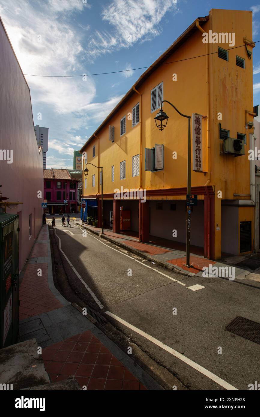 August 2024. Vertikale Ansicht. Orangefarbene Gebäudestruktur am Ann Siang Hill, einzigartige Laternenpfosten. Licht und Schatten. Chinatown Straßen. Singapur. Stockfoto