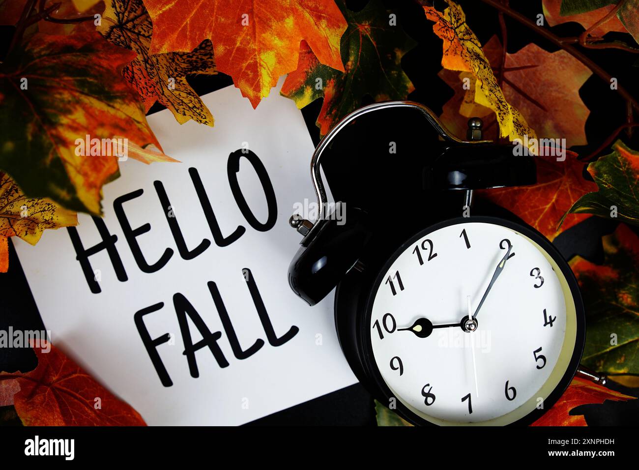 Hallo Herbst Text mit Wecker und Ahornblatt Dekoration auf hölzernem Hintergrund Stockfoto