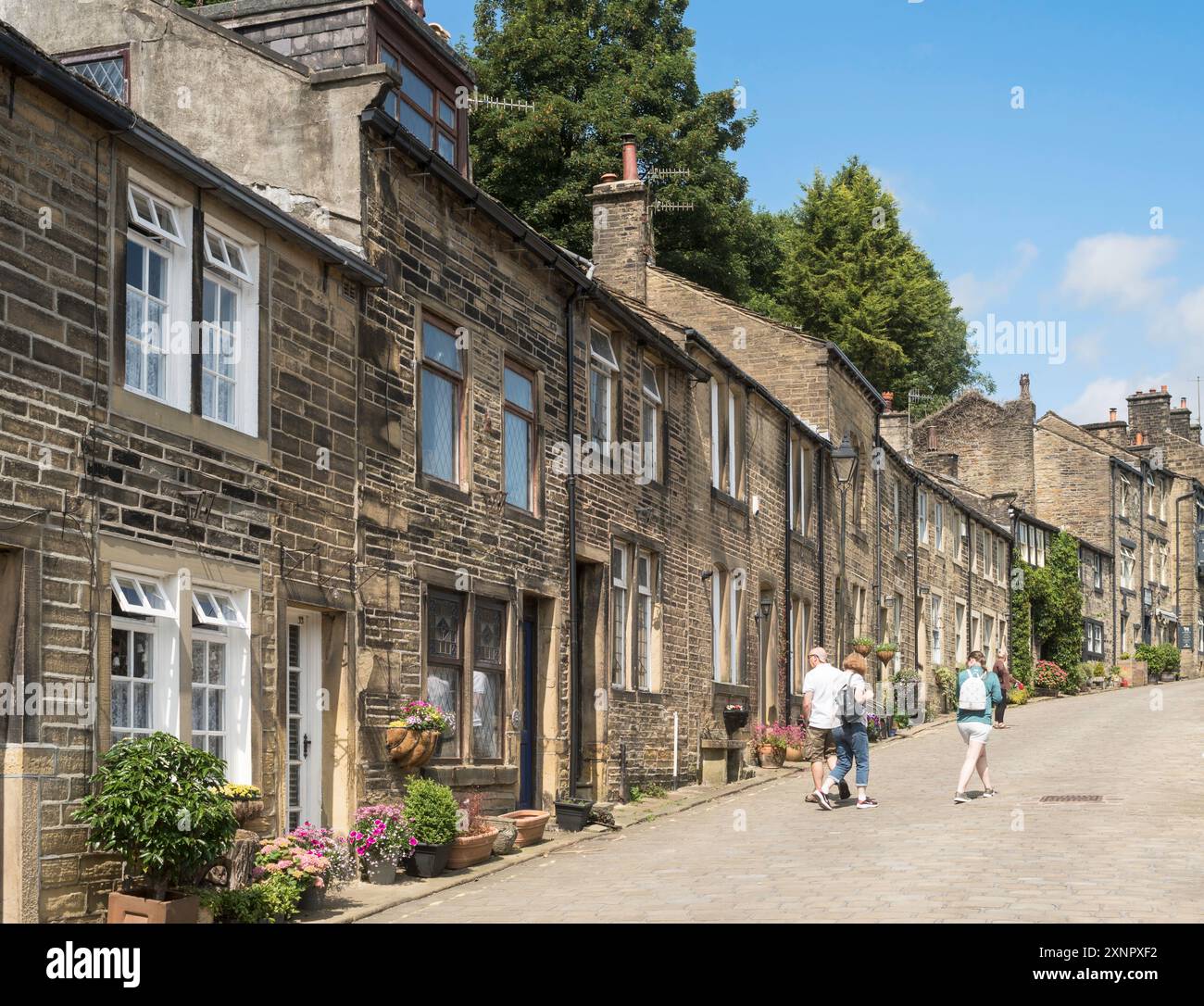 Menschen, die entlang der Howarth Main Street, Yorkshire, England, Großbritannien laufen Stockfoto