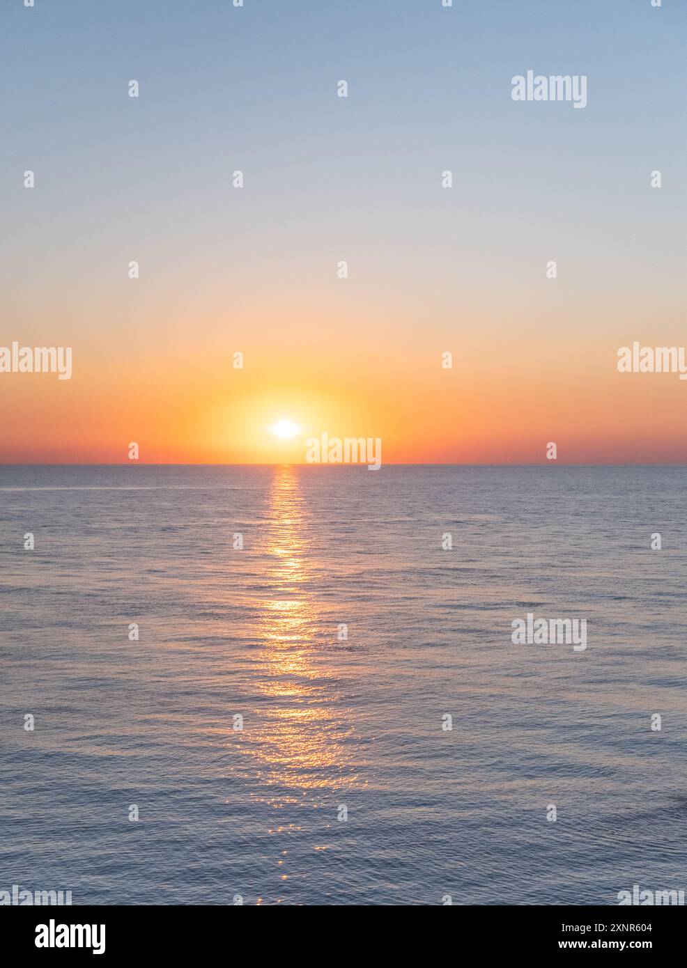 Sonnenuntergang über dem Schwarzen Meer in Batumi, Georgia. Die Sonne geht hinter Wolken unter und wirft ein goldenes Leuchten über das ruhige Wasser, was ein ruhiges und malerisches Ambiente schafft Stockfoto