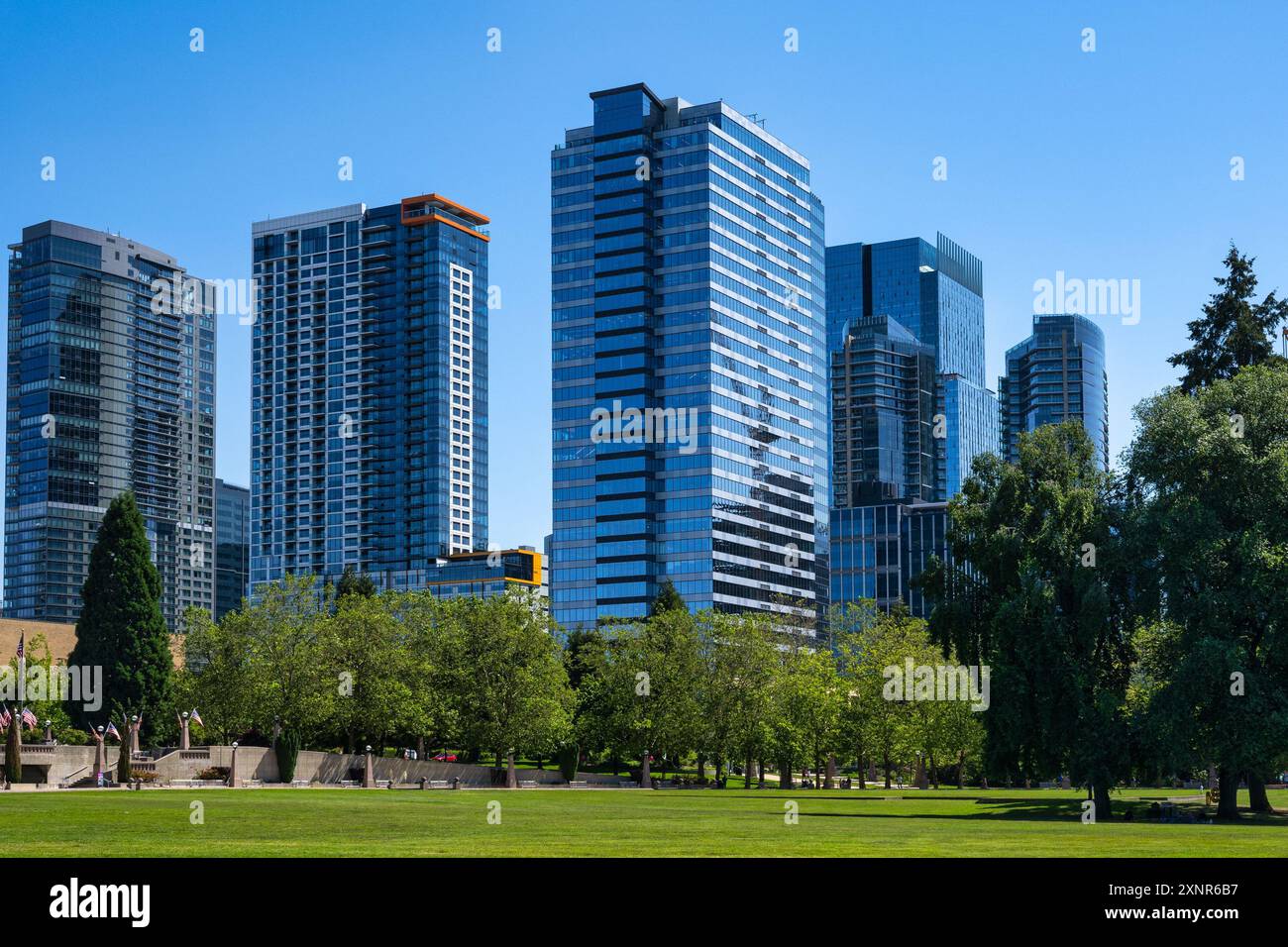 Moderne Wolkenkratzer im Stadtzentrum von Bellevue, Washington, mit einem klaren blauen Himmel und einem üppigen grünen Park im Vordergrund. Stockfoto