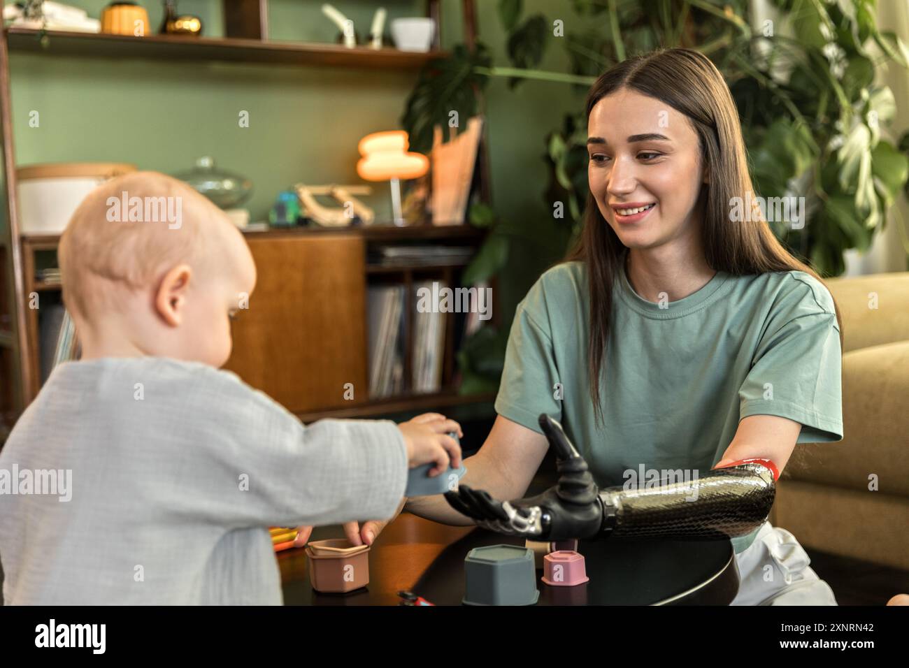 Eine junge Frau mit Prothese spielt gern mit dem Baby Stockfoto