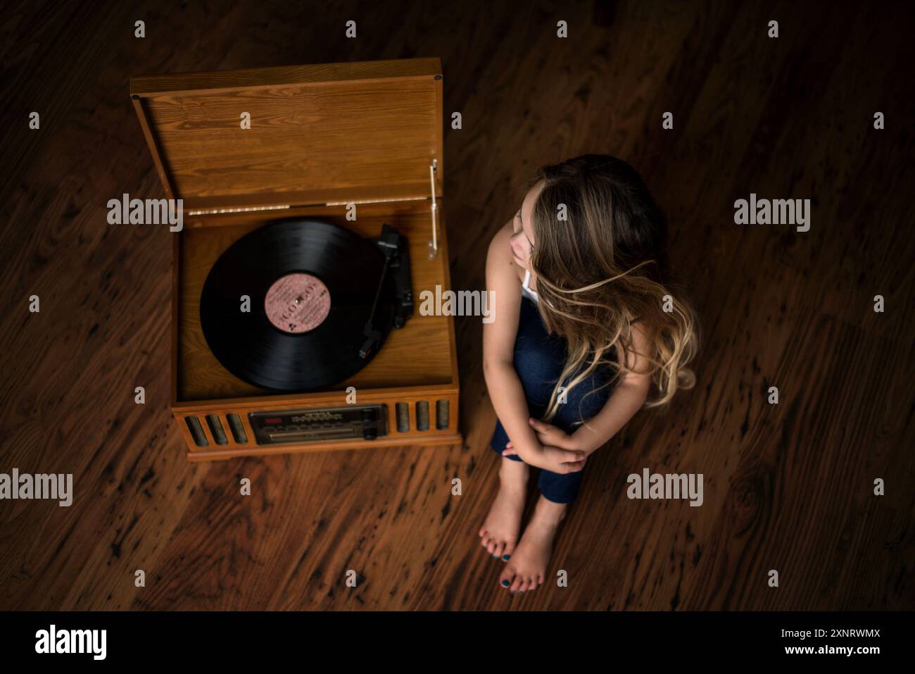 Schönes junges Mädchen, das drinnen Vinyl auf Plattenspieler hört Stockfoto