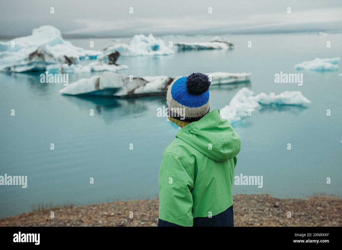 Junge, der schmelzende Eisberge in der Gletscherlagune in Island beobachtet Stockfoto