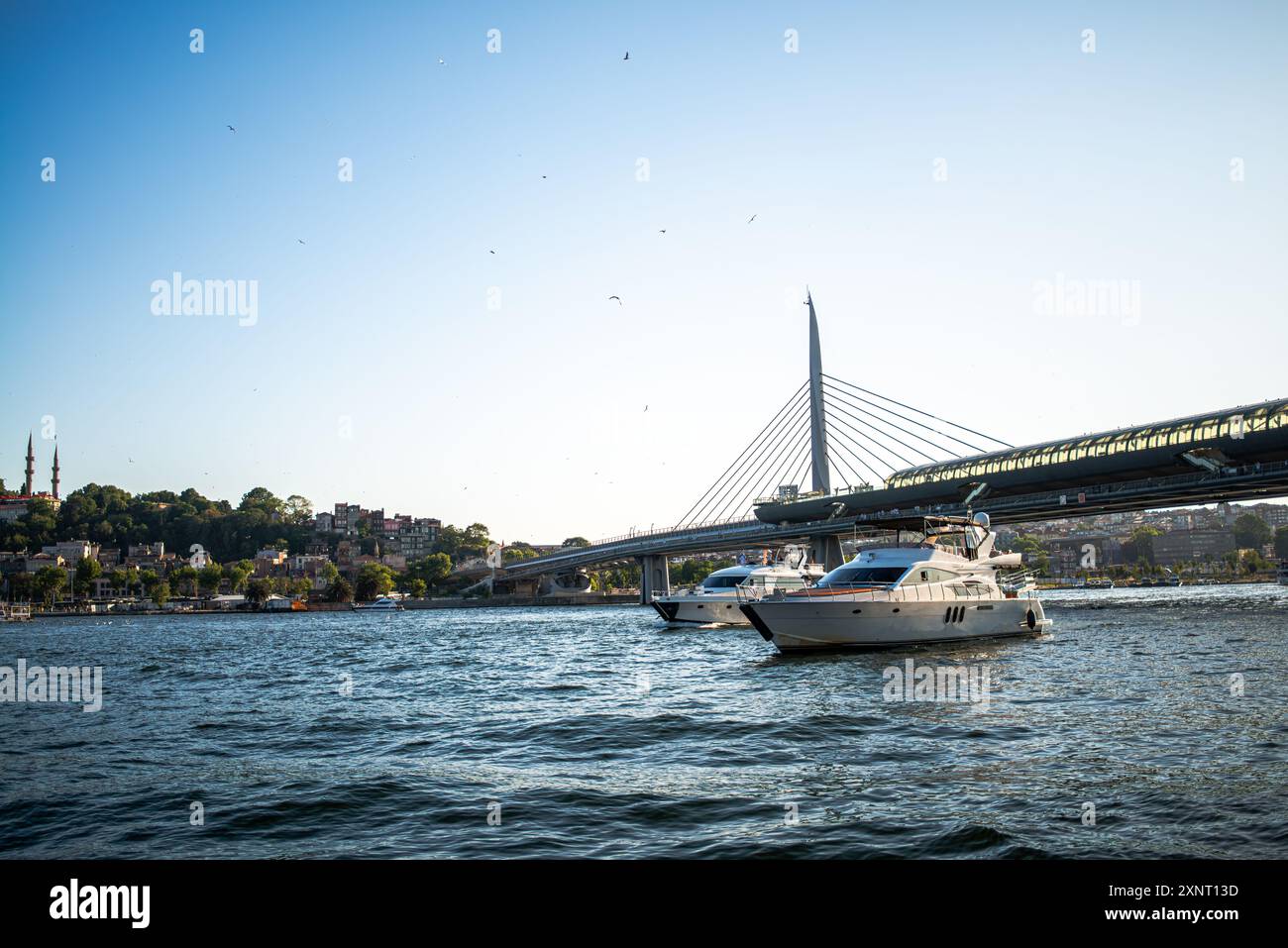 Ein atemberaubender Blick auf die Halic Metro Bridge in Istanbul mit luxuriösen Yachten, die im Vordergrund verankert sind und die Mischung aus modernem Ar der Stadt hervorheben Stockfoto