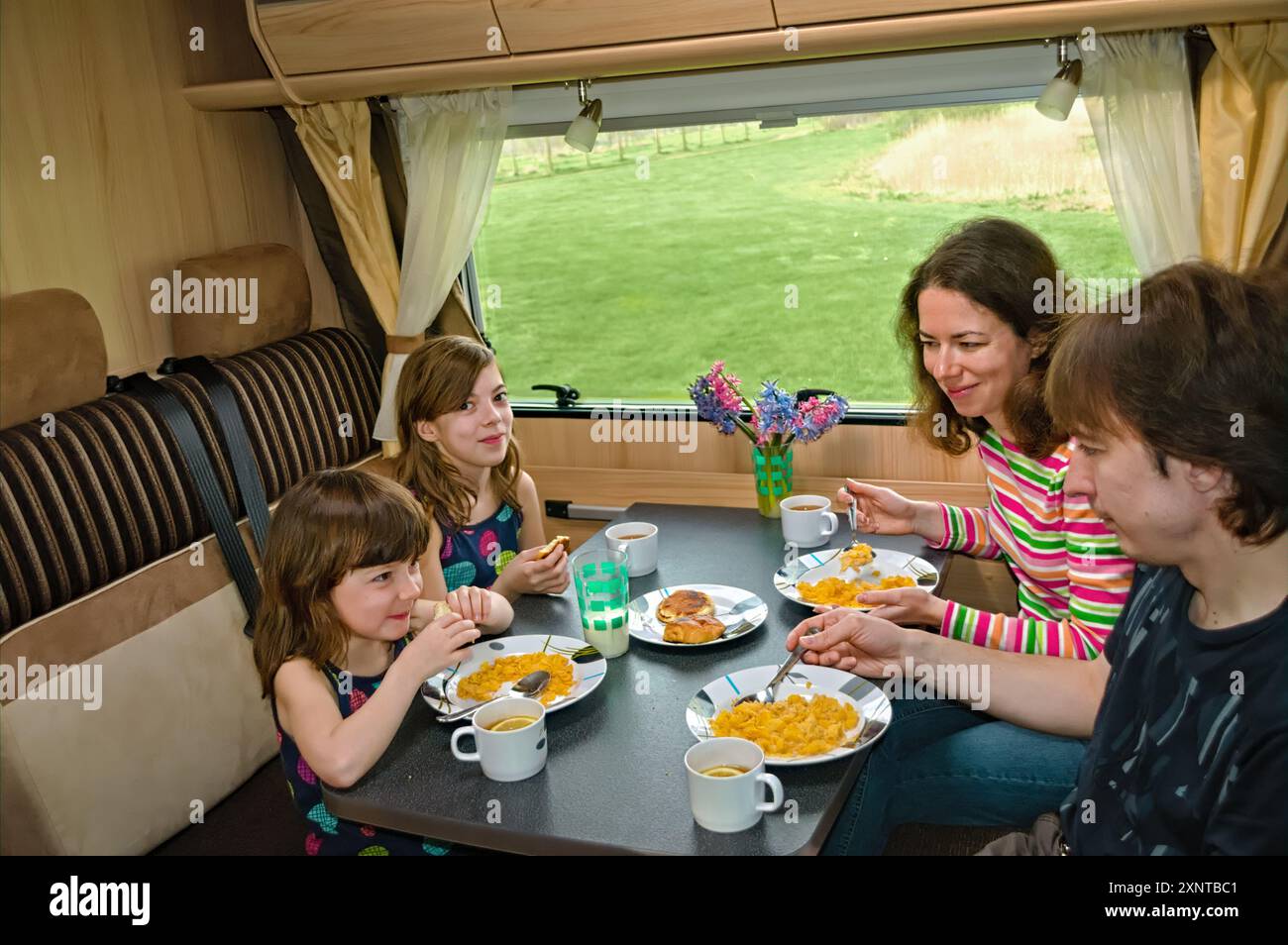 Familienessen gemeinsam im Wohnmobil, Eltern und Kinder reisen im Wohnmobil (Wohnmobil, Wohnwagen) im Familienurlaub mit Kindern Stockfoto