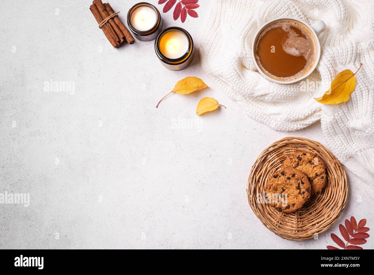 Herbstkuschelige Komposition. Tasse Schokolade oder Kaffeegetränk, Schokoladenkekse, brennende Kerzen und gelbe Herbstblätter auf weißem Hintergrund, Top V Stockfoto