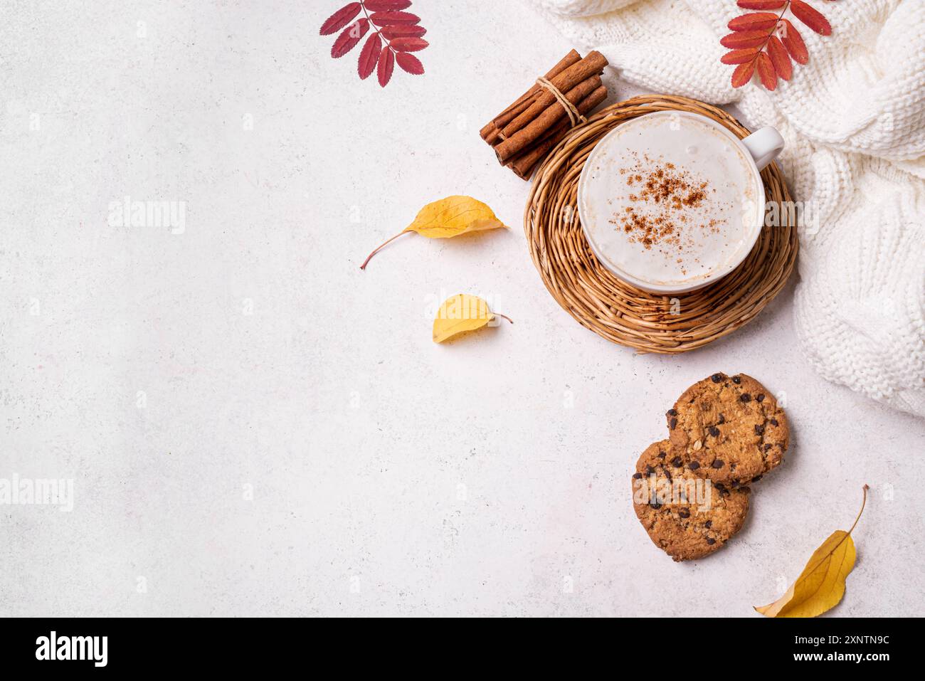 Herbstkuschelige Komposition. Tasse Cappuccino-Kaffee, gestricktes Karo, Schokoladen-Chip-Cookies und gelbe Herbstblätter auf weißem Hintergrund, Draufsicht, Kopie Stockfoto