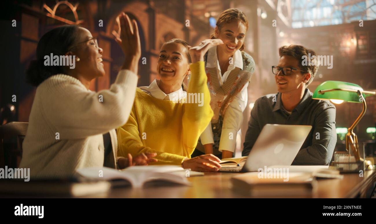 Verschiedene Gruppe von Studenten, die an einem Projekt in einer modernen Bibliothek zusammenarbeiten. Junge Erwachsene, die sich mit Diskussionen beschäftigen, Laptop für Forschung und E-Learning nutzen, freudige akademische Interaktion erleben Stockfoto
