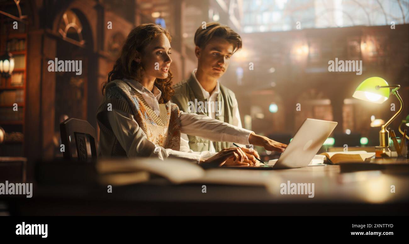 Engagiertes Jungkaukasisches Paar, das zusammen in einer Vintage-Bibliothek studiert, mit einem Laptop und umgeben von Büchern. Die warme Beleuchtung unterstreicht die fokussierten Ausdrucksformen und die gemütliche akademische Umgebung Stockfoto