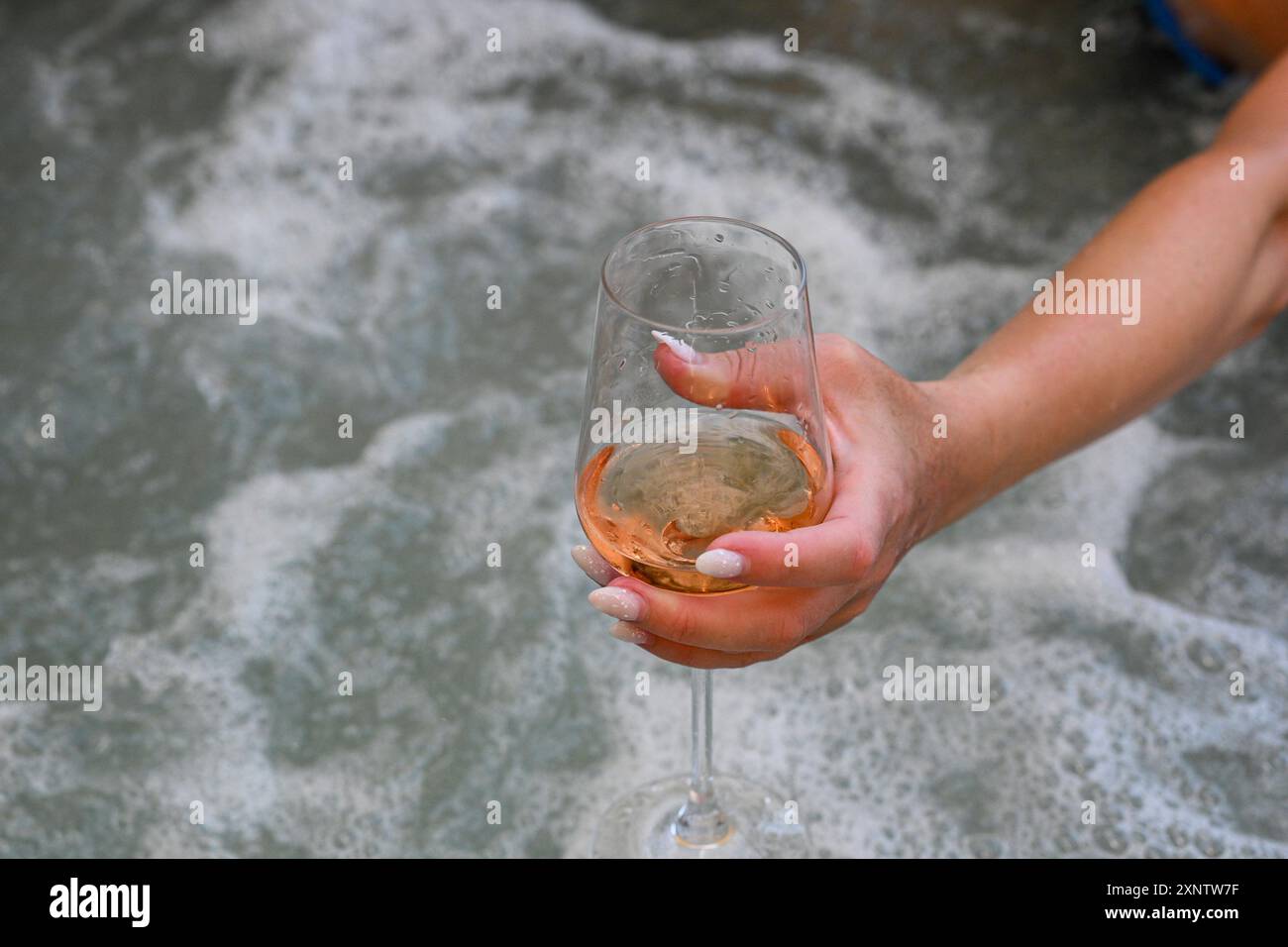 Eine Frau genießt ein entspannendes Bad mit einem Glas Wein. Stockfoto