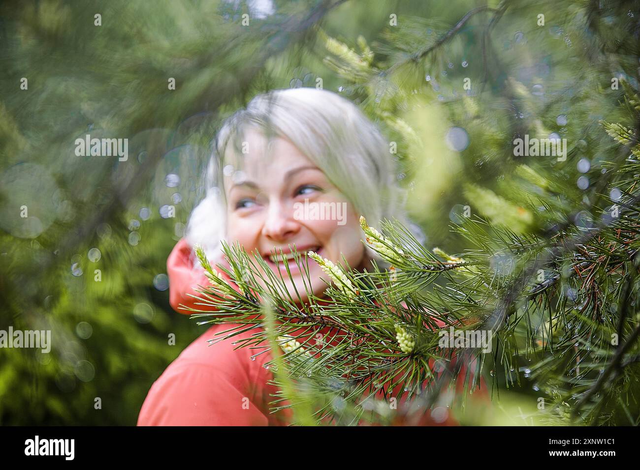 Schöne Frau in einer Korral Kapuzenjacke im Wald nach dem Regen Stockfoto