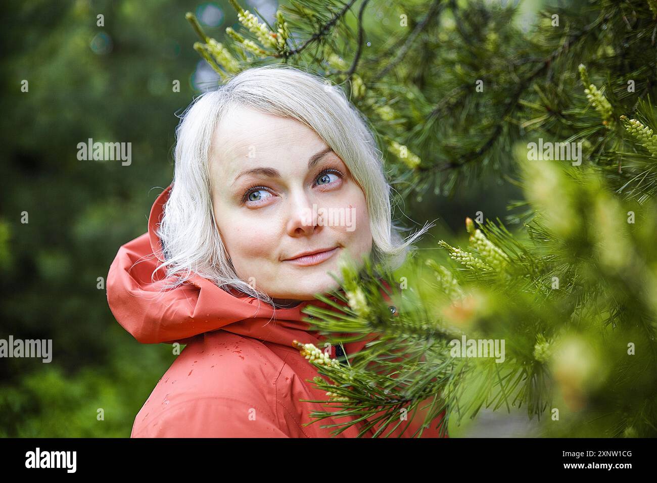 Schöne Frau in einer Korral Kapuzenjacke im Wald nach dem Regen Stockfoto