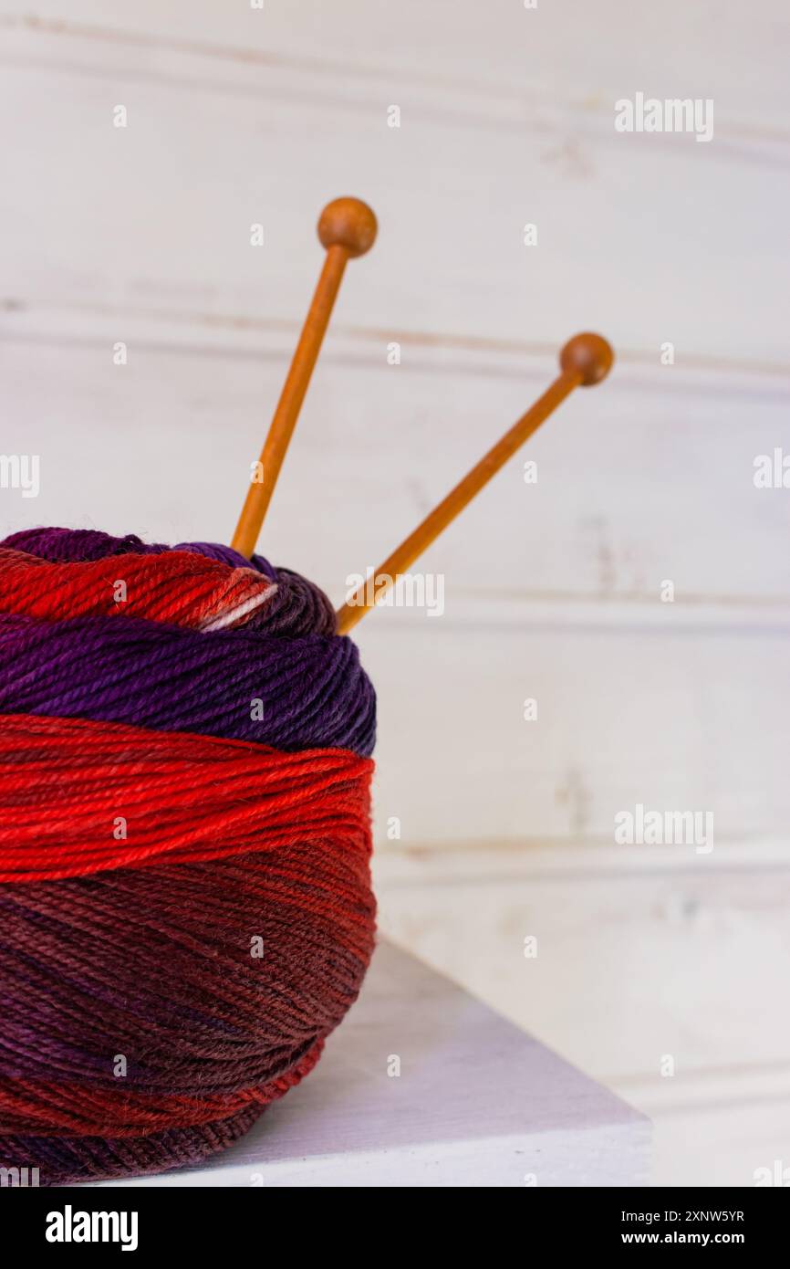 Bunte Stoffkugel mit Holzstricknadeln. Buntes Wollgarn mit Stricknadeln auf weißem Hintergrund. Handarbeit mit Kopierraum. Stockfoto