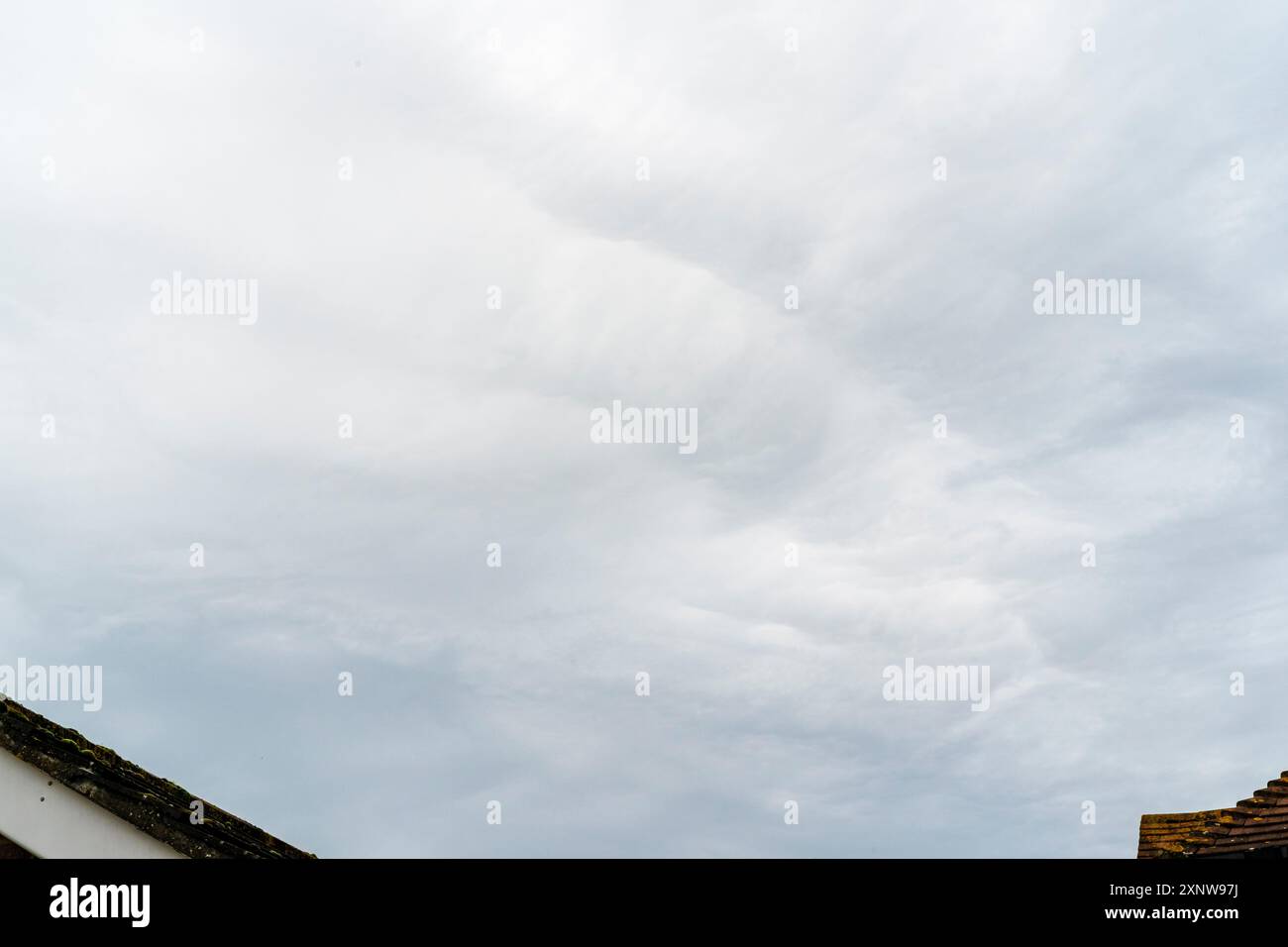 Graue niedrige Wolkenschicht über Dächern in Großbritannien. Stratocumulus-Wolken bilden ein Muster aus Licht und Schatten. Stockfoto