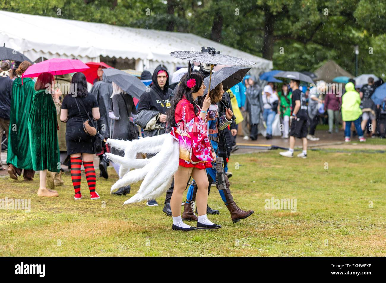 Cottbus, Deutschland. August 2024. Die Teilnehmer des Elbenwald Festivals laufen im Regen über das Festgelände im Spreeauenpark. Das Elbenwald Festival ist in erster Linie ein Treffpunkt für Fans populärer Science-Fiction- und Fantasy-Serien wie Harry Potter, Star Wars, Lord of the Rings und Marvel Comics. Vermerk: Frank Hammerschmidt/dpa/Alamy Live News Stockfoto