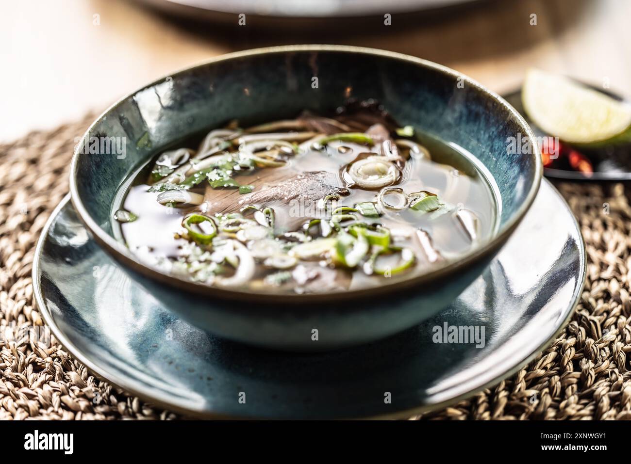 Pho Bo vietnamesische frische Reisnudelsuppe mit Rindfleisch, Zwiebeln, Limette, Kräutern und Chili-Dekoration. Stockfoto
