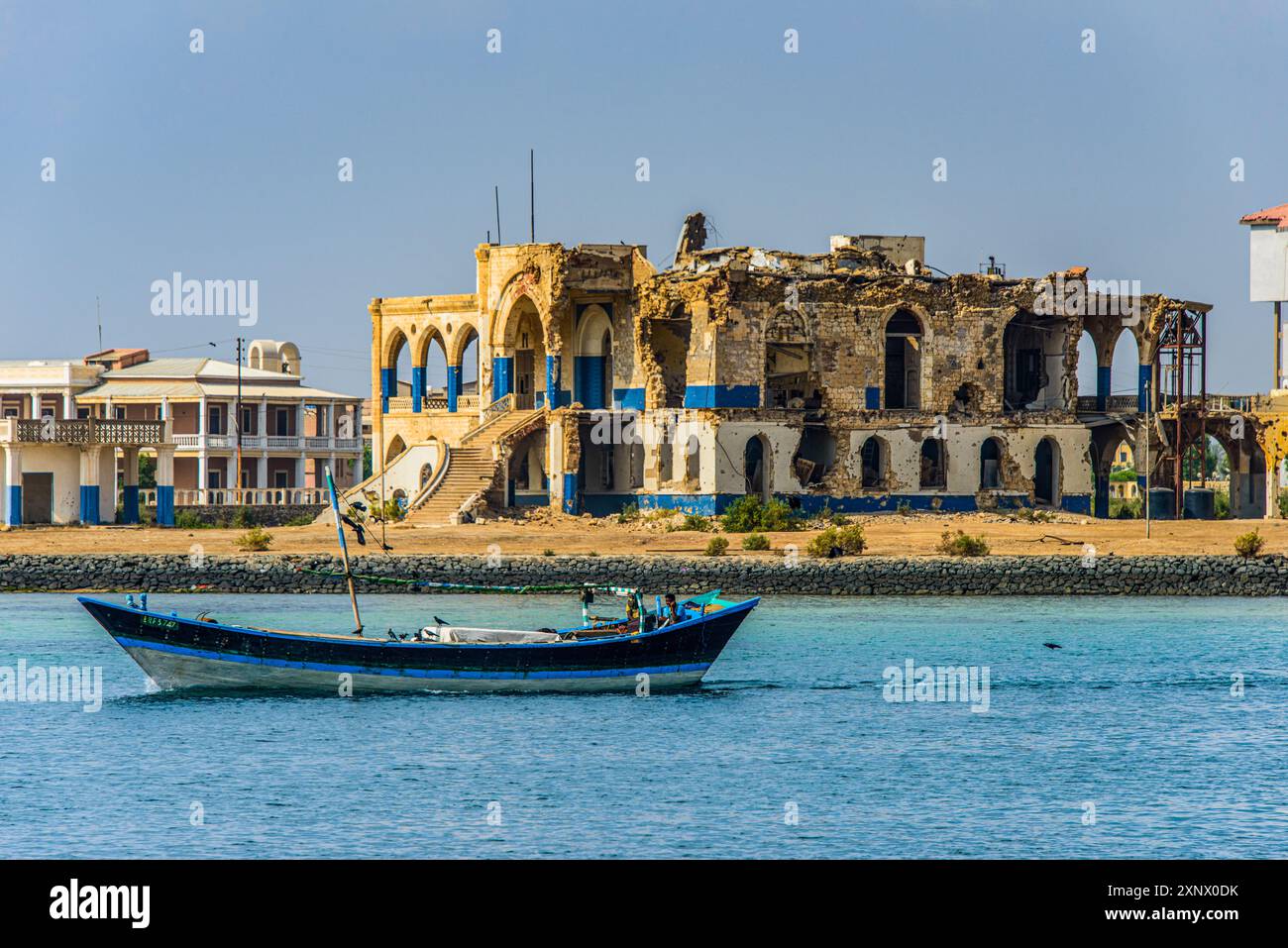 Fischerboot schwimmt vor dem bombardierten Regierungspalast in der Altstadt von Massawa, Eritrea, Afrika Stockfoto