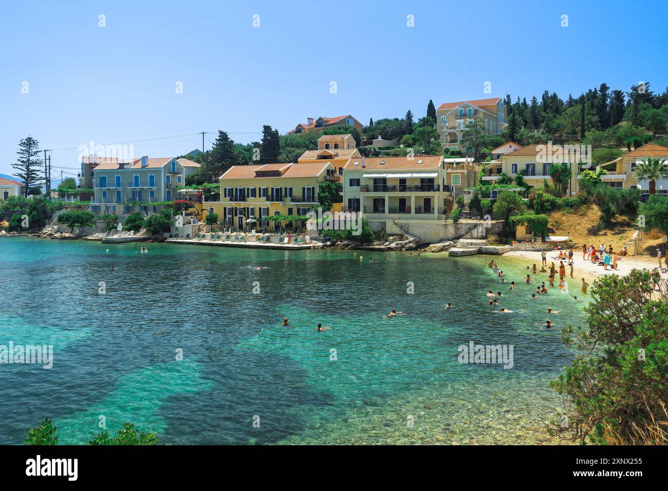 Fiscardo Dorf mit flachen Häusern mit roten Ziegeln Dächern am Strand mit Badenden, Fiscardo, Kefalonia, Ionische Insel, griechische Inseln, Griechenland, Europa Stockfoto