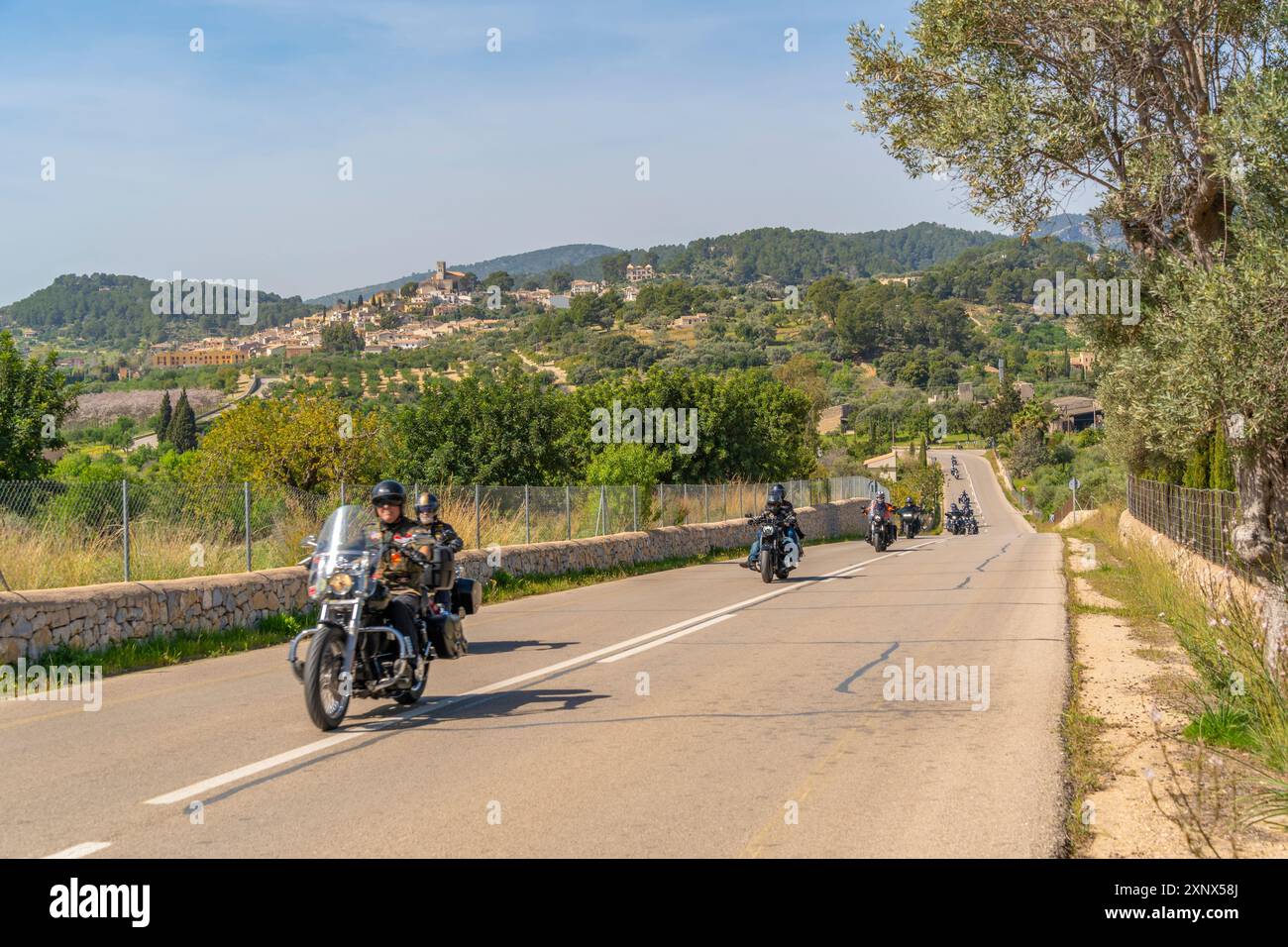 Blick auf Motorradfahrer und die auf einem Hügel gelegene Stadt Selva, Mallorca, Balearen, Spanien, Mittelmeer, Europa Stockfoto