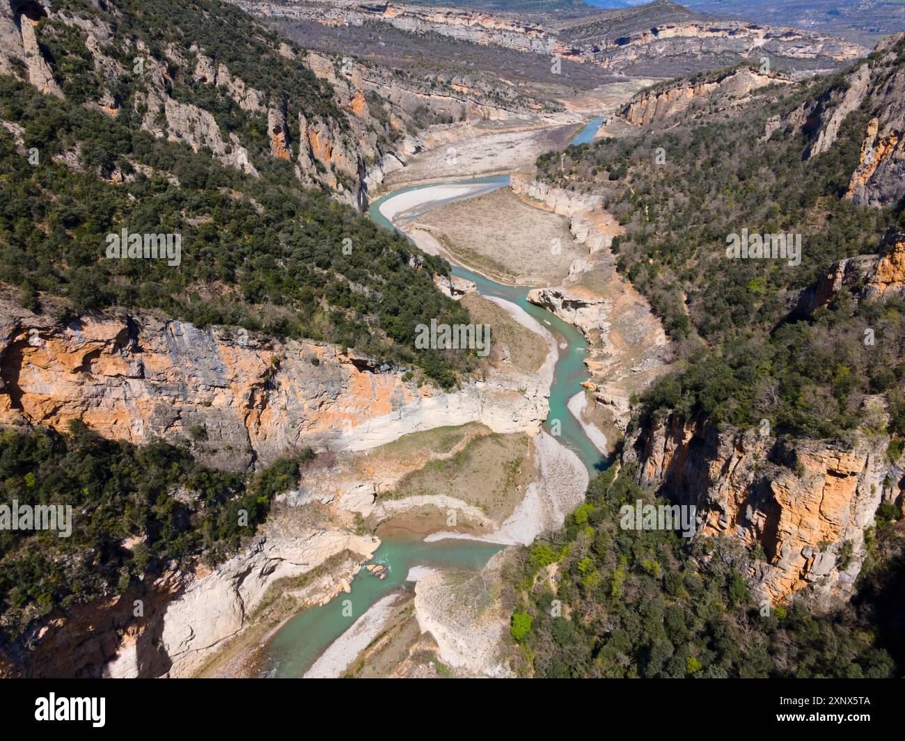 Aus der Vogelperspektive auf eine felsige Schlucht mit einem sich windenden Fluss und dicht bewachsenen Klippen, aus der Vogelperspektive auf die Schlucht Congost de Mont-rebei, Noguera Ribagorcana Stockfoto