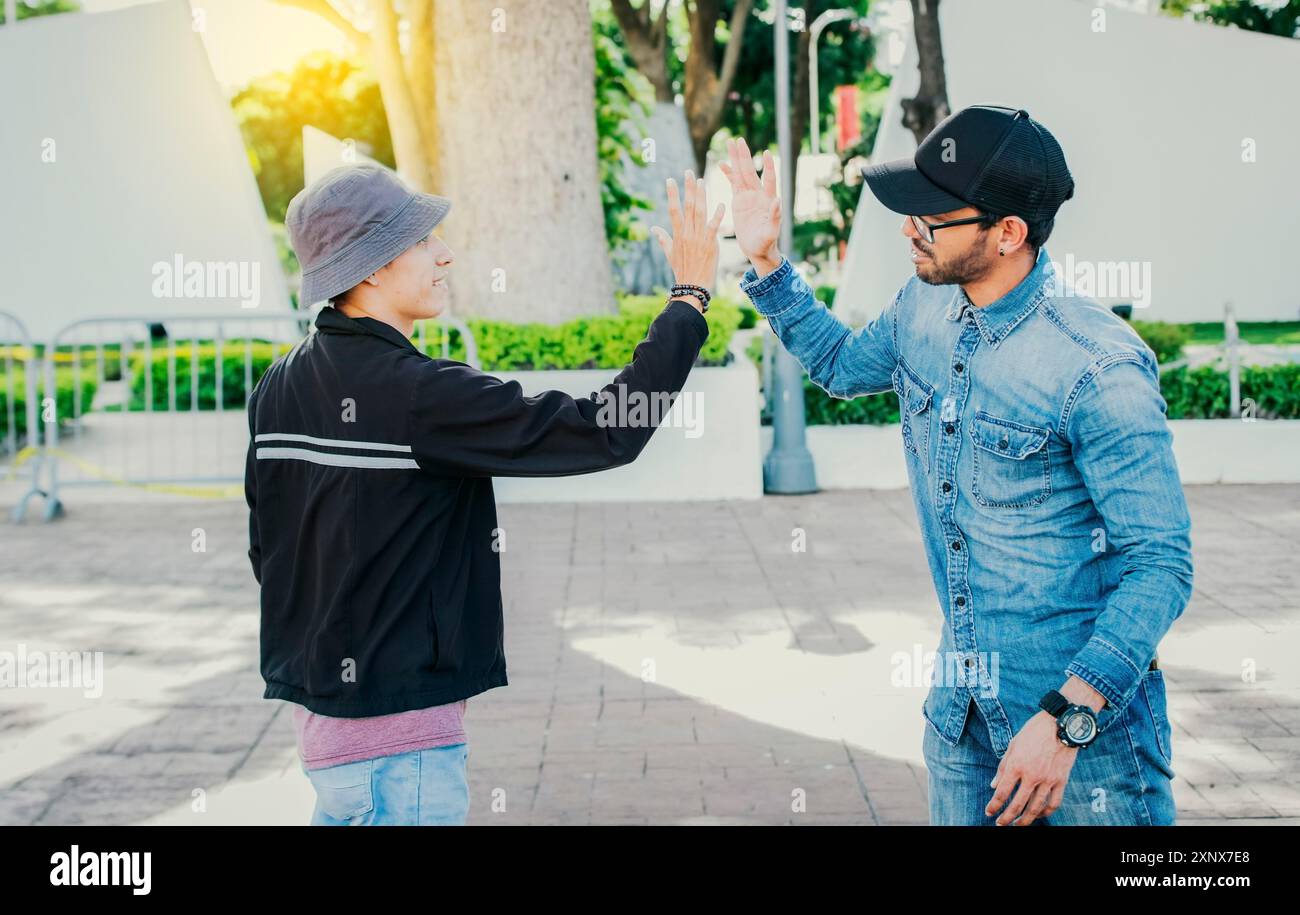 Die Leute grüßen einander und schütteln sich die Hände auf der Straße. Zwei Teenager-Freunde schütteln draußen die Hand Stockfoto