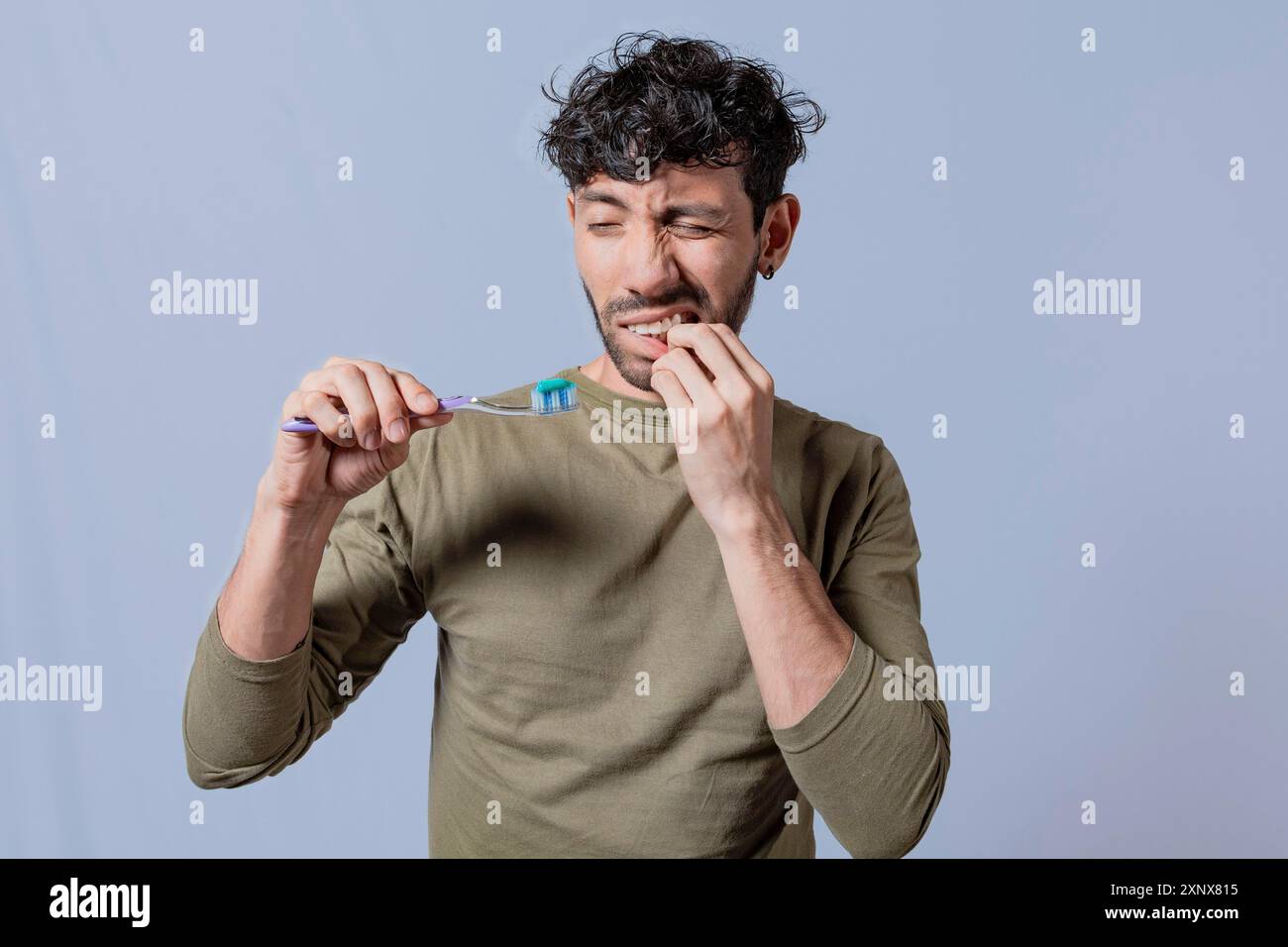 Junger Mann, der Zahnbürste mit Zahnfleischschmerzen hält. Mann, der Zahnbürste mit Zahnfleischschmerzen hält, Leute, die Zahnbürste mit Zahnfleischproblem isoliert halten Stockfoto